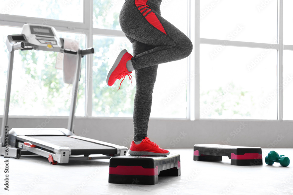 Woman doing exercises on stepper in gym