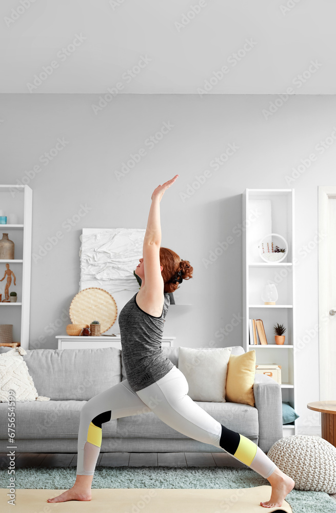 Beautiful young woman in sportswear practicing yoga at home