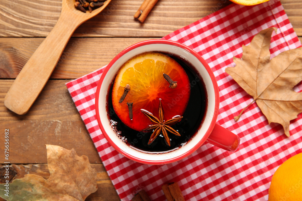 Cup of hot mulled wine with orange on wooden background