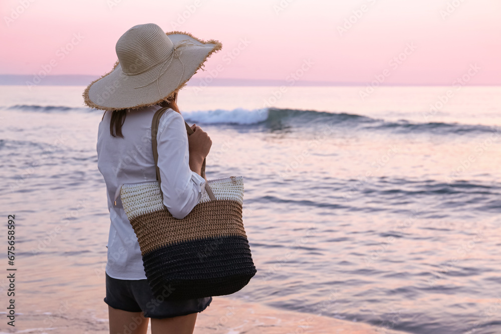 Woman with stylish beach bag near sea