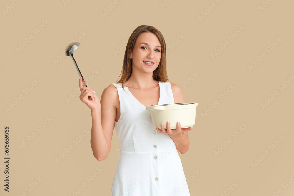 Young woman with ladle and cooking pot of chicken soup on beige background