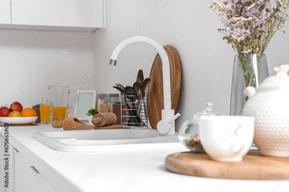 White counters with sink and utensils in interior of modern kitchen, closeup