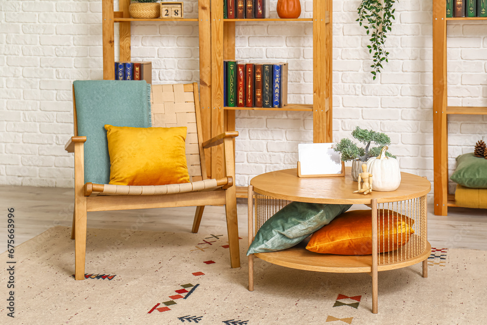 Interior of stylish living room with armchair, table and bookshelves