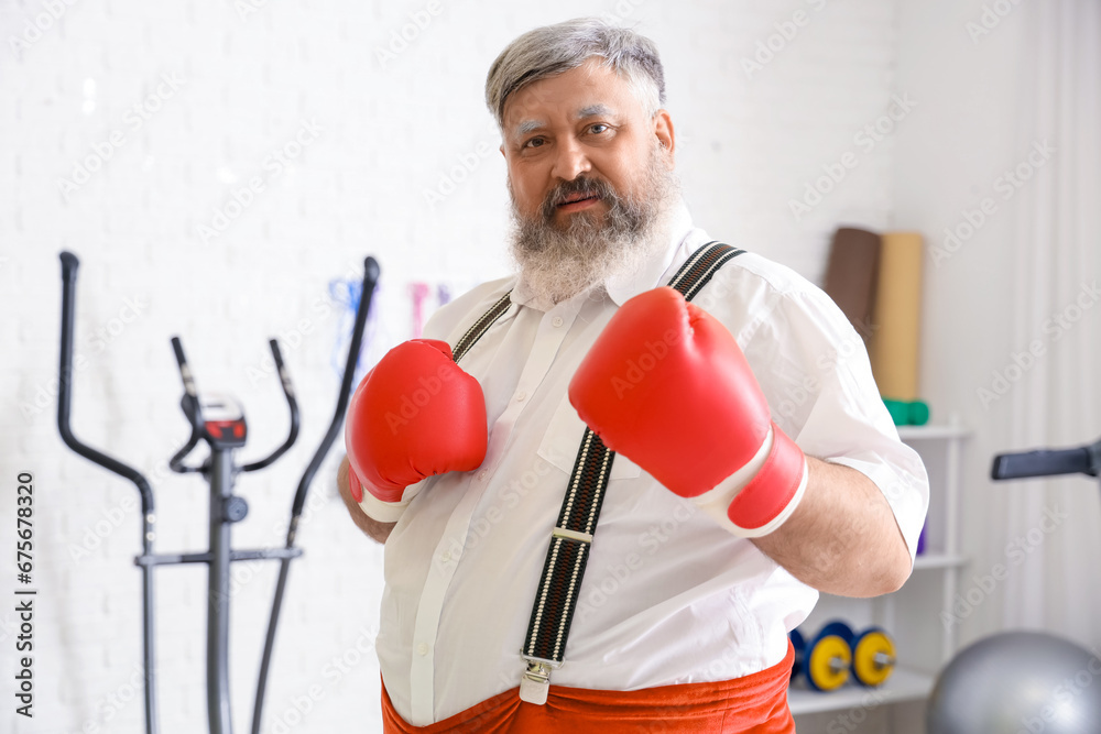 Sporty Santa Claus with boxing gloves training in gym