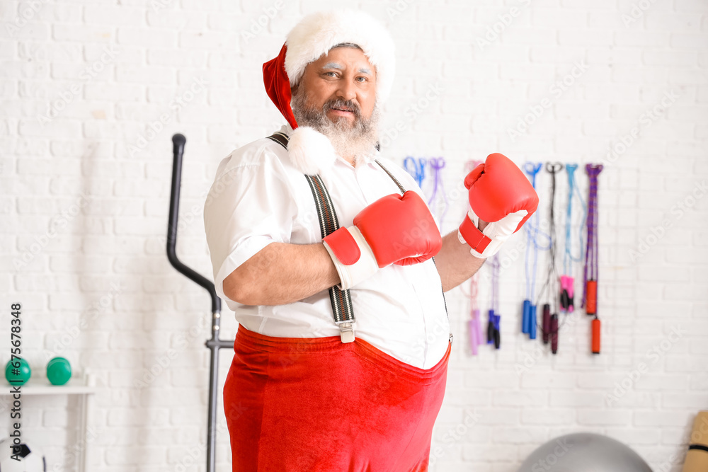 Sporty Santa Claus with boxing gloves training in gym