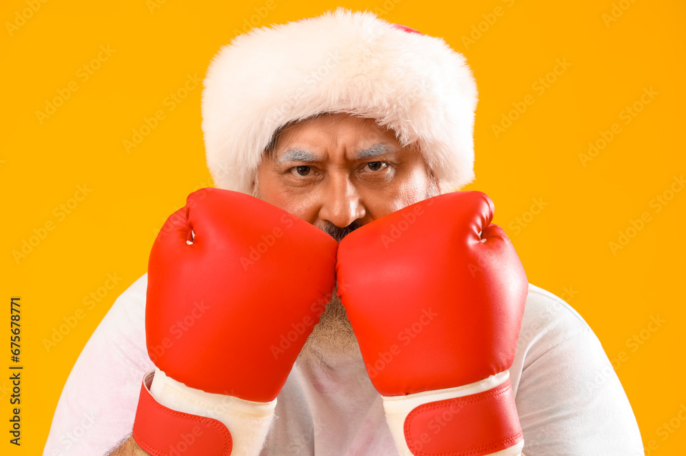 Sporty Santa Claus with boxing gloves on yellow background, closeup