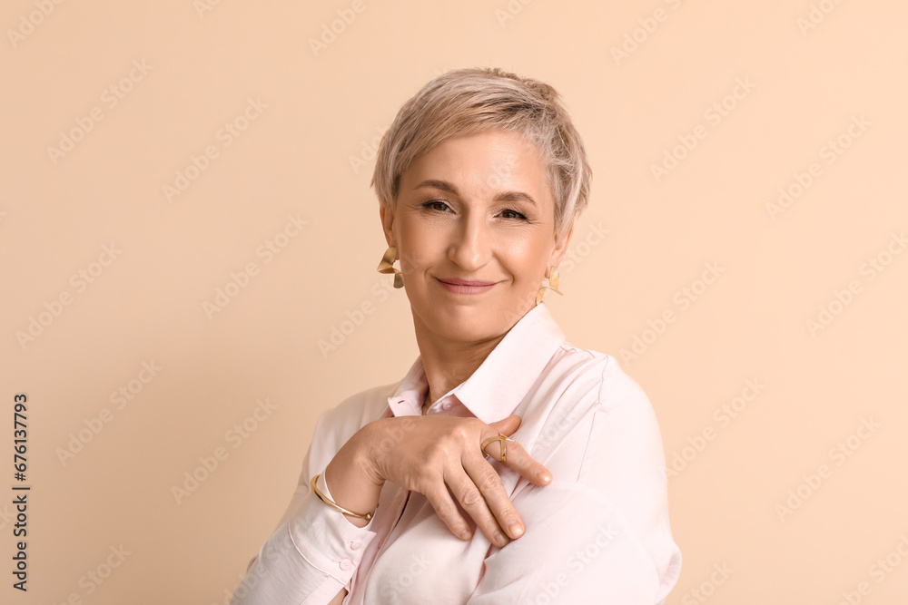 Mature blonde woman smiling on beige background, closeup