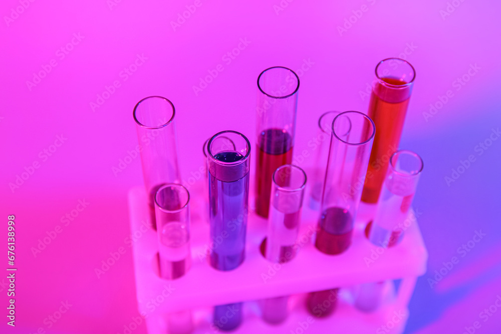 Test tubes with different samples in stand on colorful background, closeup