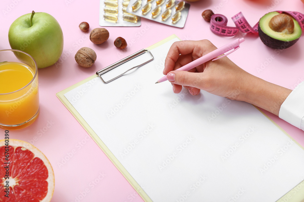 Female doctor with blank clipboard, pen and healthy food on color background, closeup