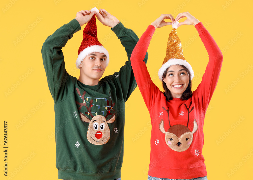 Beautiful young couple in Christmas clothes on yellow background