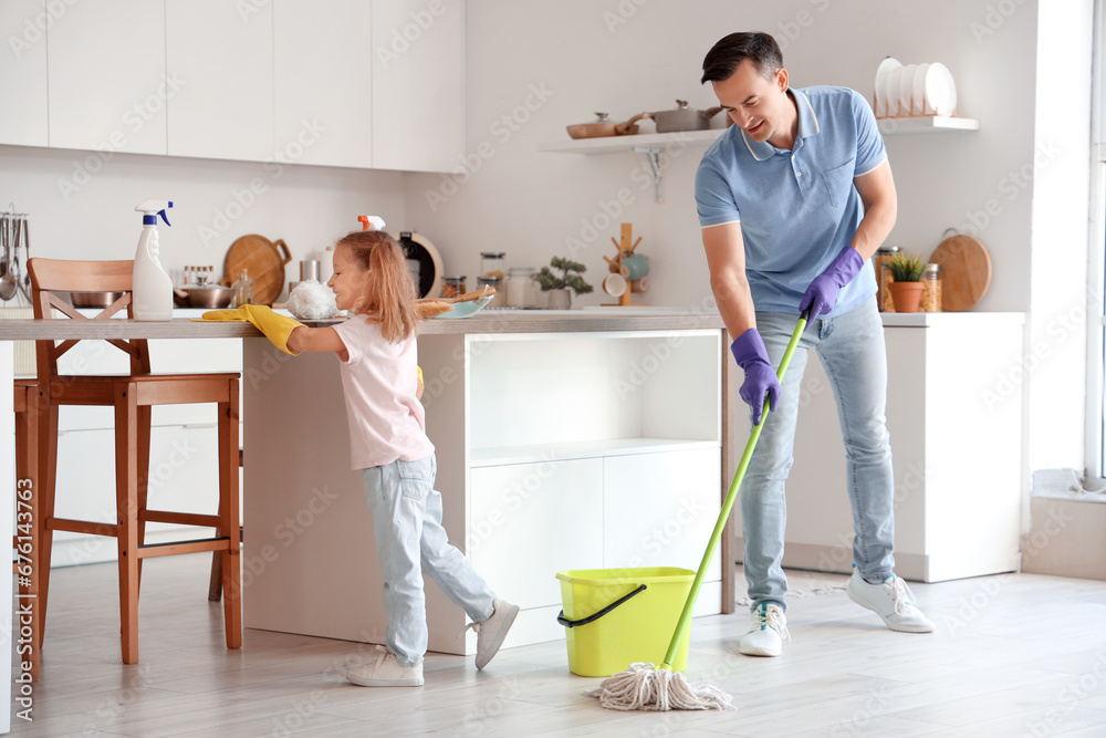 Cute little girl with her dad cleaning in kitchen