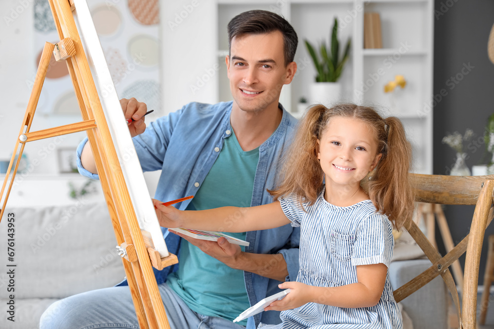 Cute little girl with her dad drawing at home