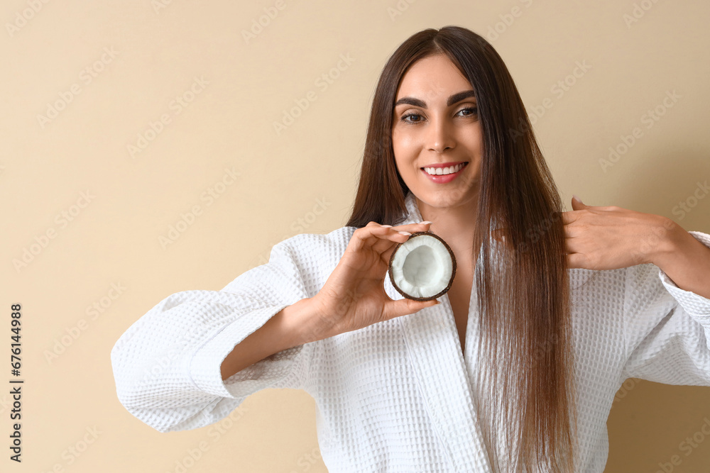 Beautiful young woman with coconut on beige background