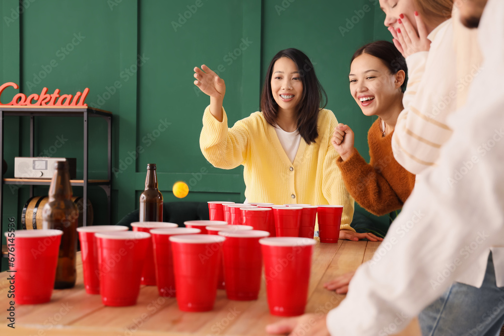 Group of young friends playing beer pong at party