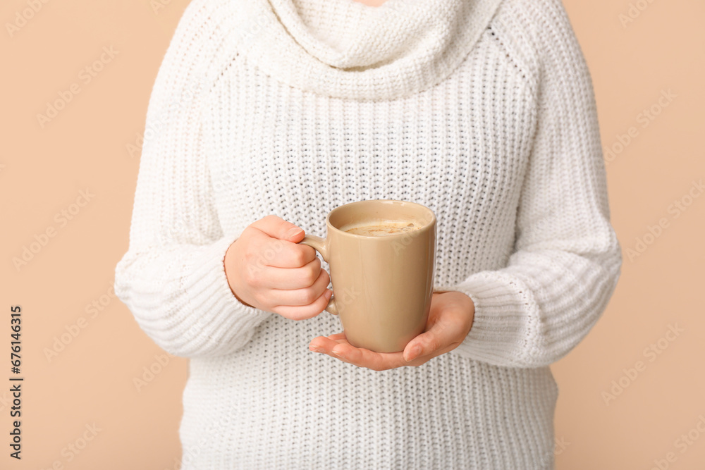 Woman with cup of coffee on beige background