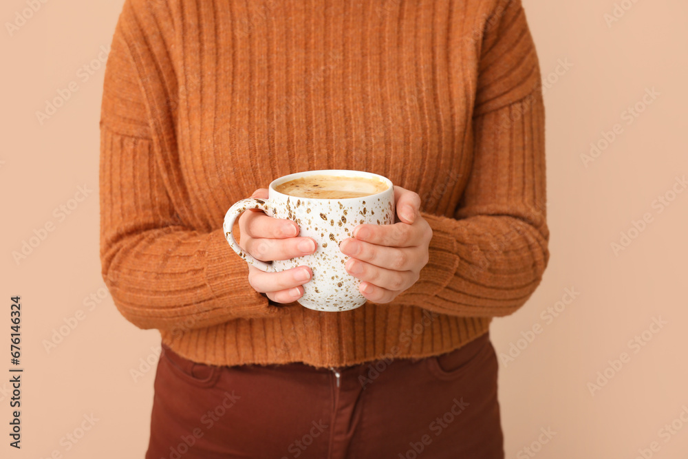 Woman with cup of coffee on beige background