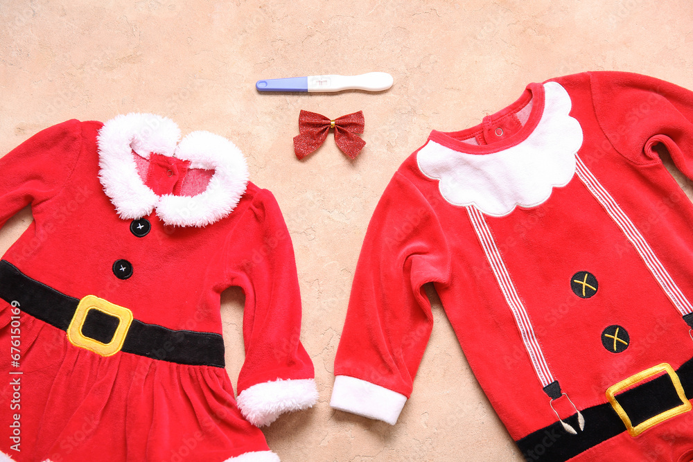 Baby Santa costumes and pregnancy test on color background, closeup