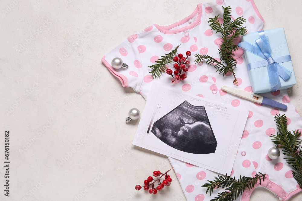 Composition with baby clothes, sonogram image and Christmas decorations on light background