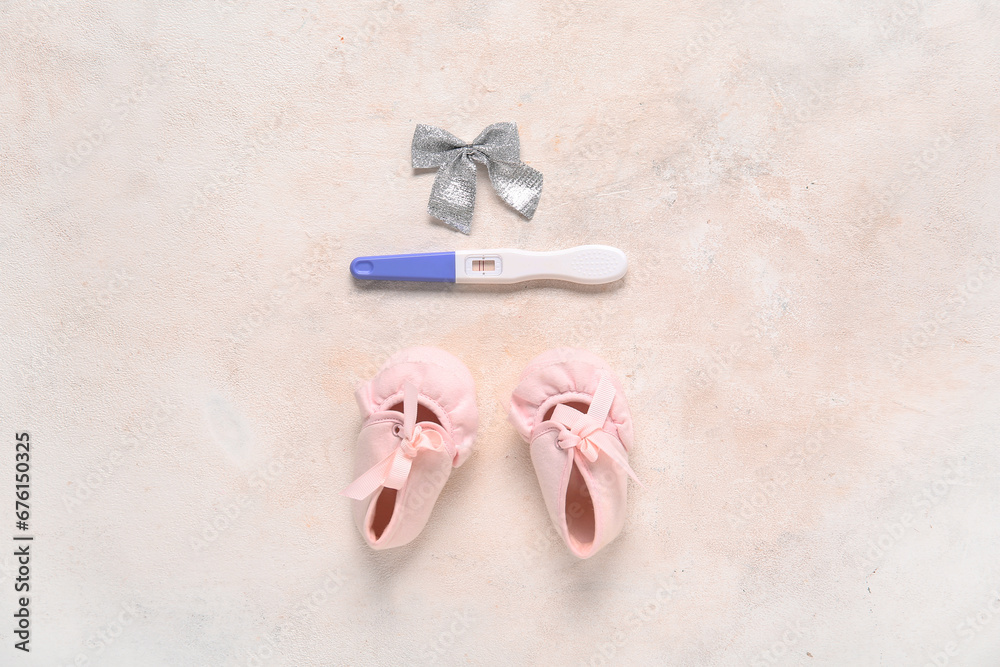 Stylish baby booties, pregnancy test and Christmas bow on color background