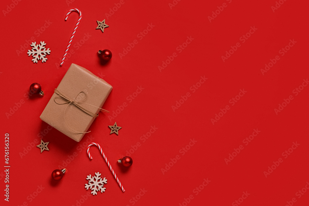 Gift box with Christmas decorations and candy canes on red background