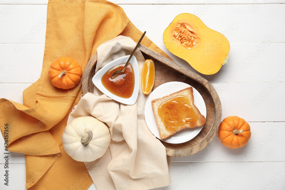 Plate of toast with sweet pumpkin jam and orange on white wooden background