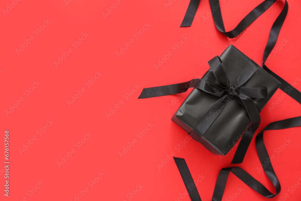 Gift box and ribbon on red background. Black Friday