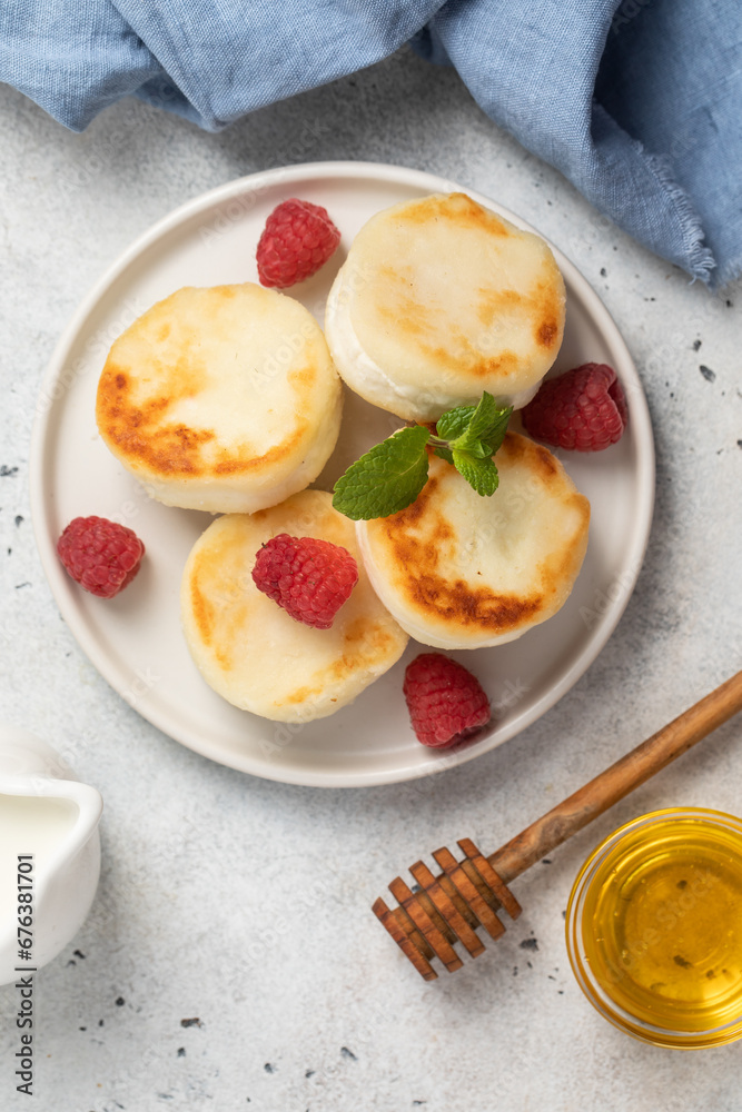 Cottage cheese fritters or syrniki served with raspberries.