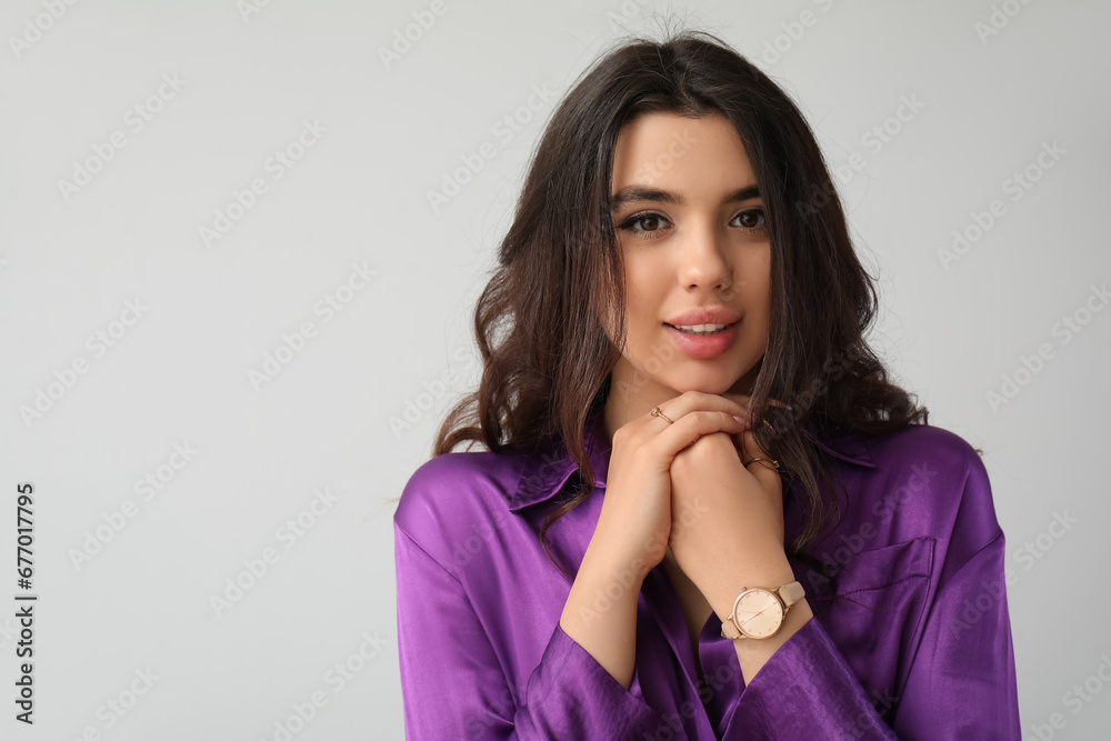 Elegant beautiful young woman with wristwatch on grey background