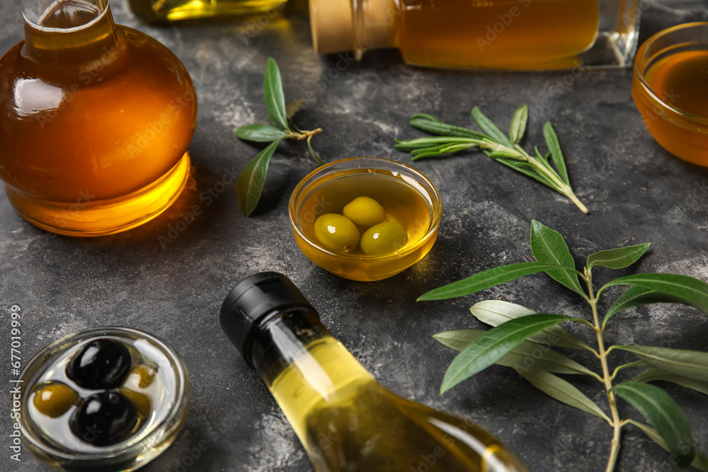 Bowls, jug and bottles of fresh olive oil on black background