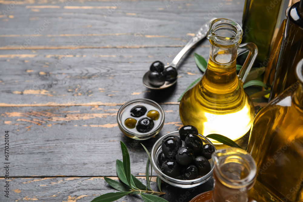 Bowls with olives and jug of oil on black wooden background