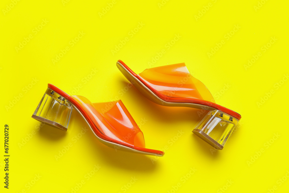 Stylish orange sandals on yellow background