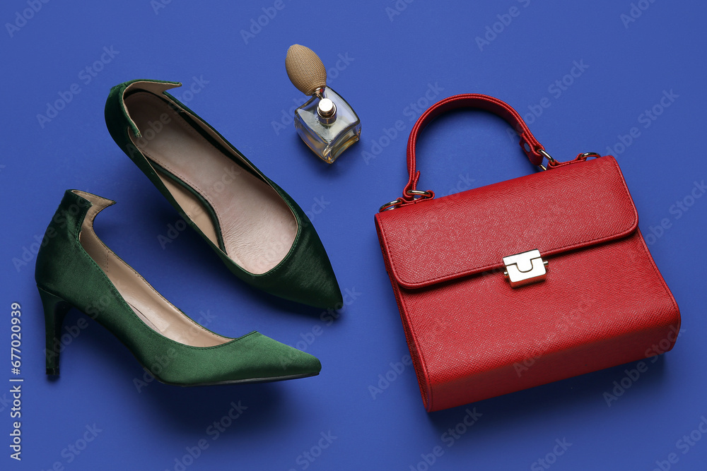 Stylish green high heels with handbag and perfume on blue background