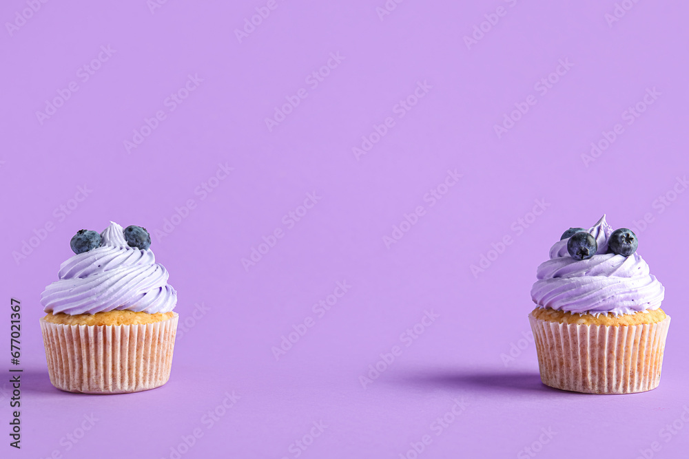 Tasty cupcakes with blueberries on lilac background