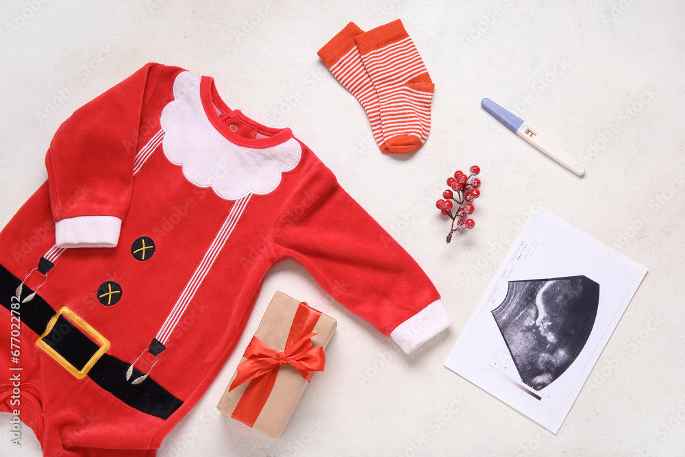 Composition with baby Santa costume, sonogram image and Christmas gift on light background