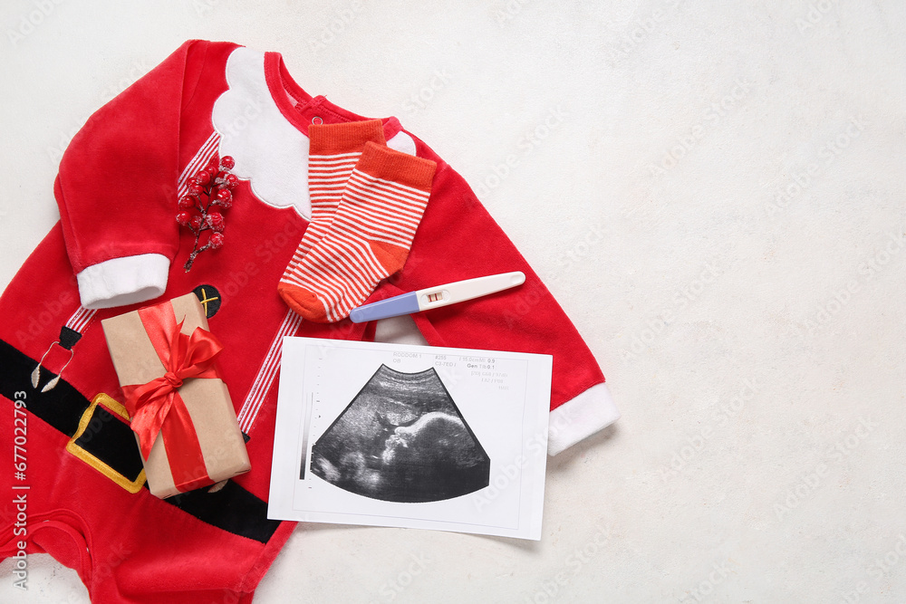 Composition with baby Santa costume, sonogram image and Christmas gift on light background