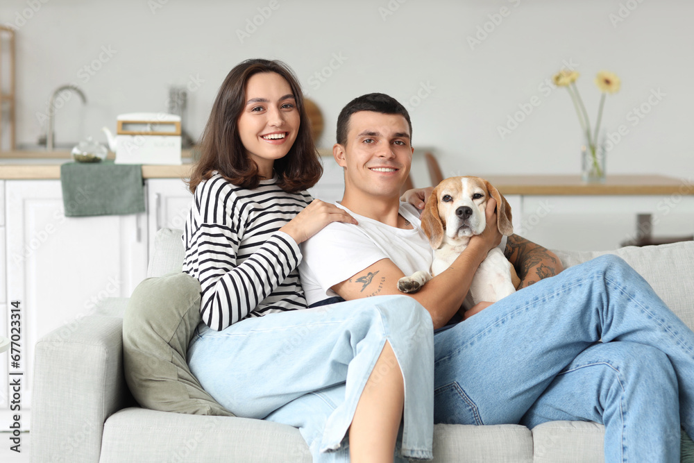 Young couple with cute Beagle dog at home