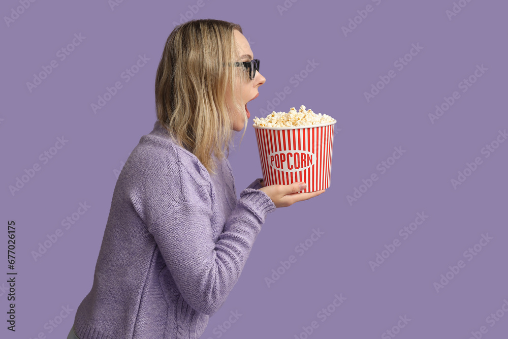 Young woman in 3D glasses with bucket of popcorn on purple background