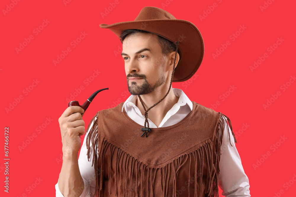 Handsome cowboy with smoking pipe on red background, closeup