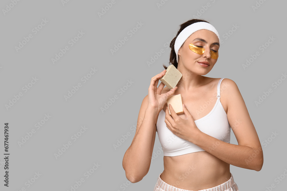 Young woman with soap bars on light background