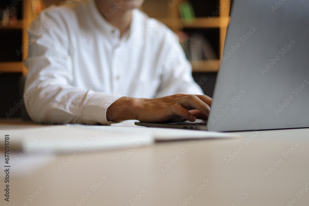 Happy male students working with laptops, reading books and doing homework in university library.