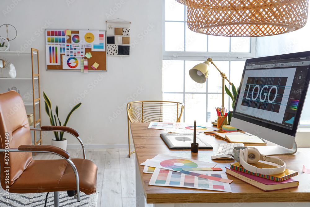 Graphic designers workplace with computer, tablet and paint palettes in office