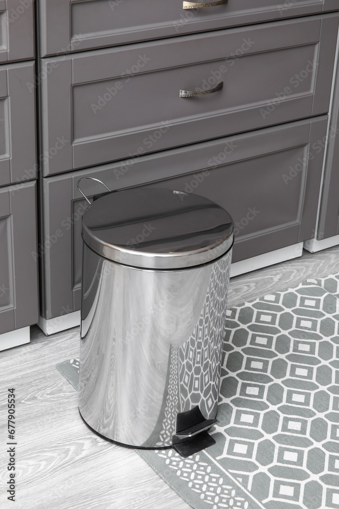 Metallic trash bin on floor in modern kitchen