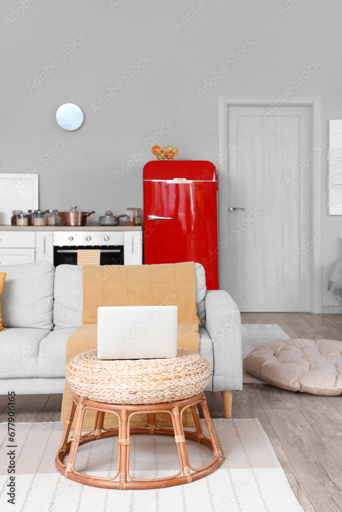 Interior of kitchen with red fridge, counters, sofa and laptop computer