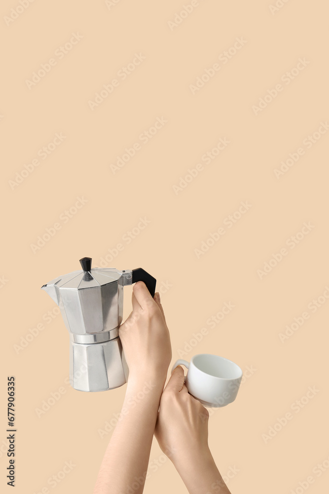 Female hands holding cup and geyser coffee maker on beige background