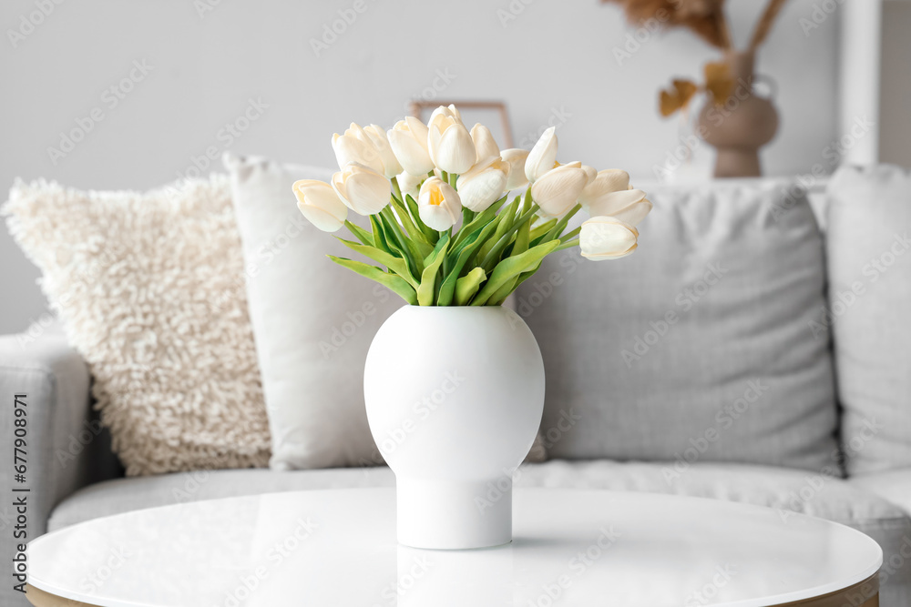 Vase with blooming white tulip flowers on coffee table in living room, closeup