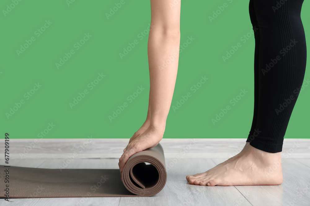 Sporty woman with fitness mat near green wall in gym, closeup