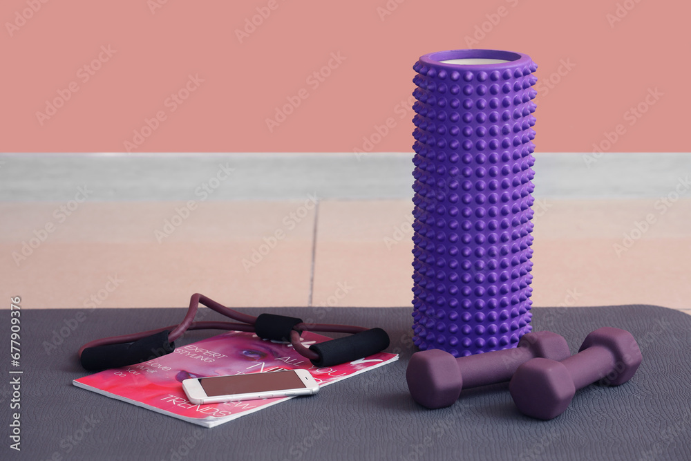 Sports equipment with mobile phone and magazine on fitness mat in gym