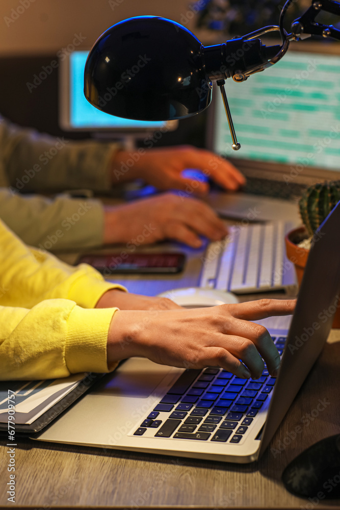 Female programmer working with laptop in office at night, closeup