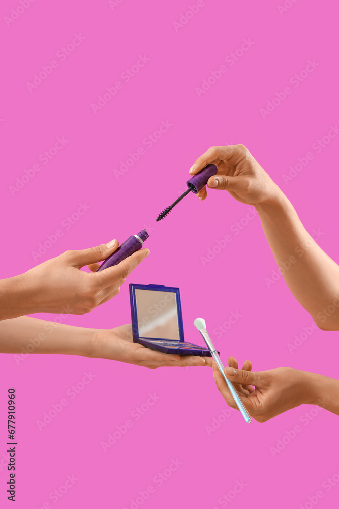 Women with makeup products on pink background