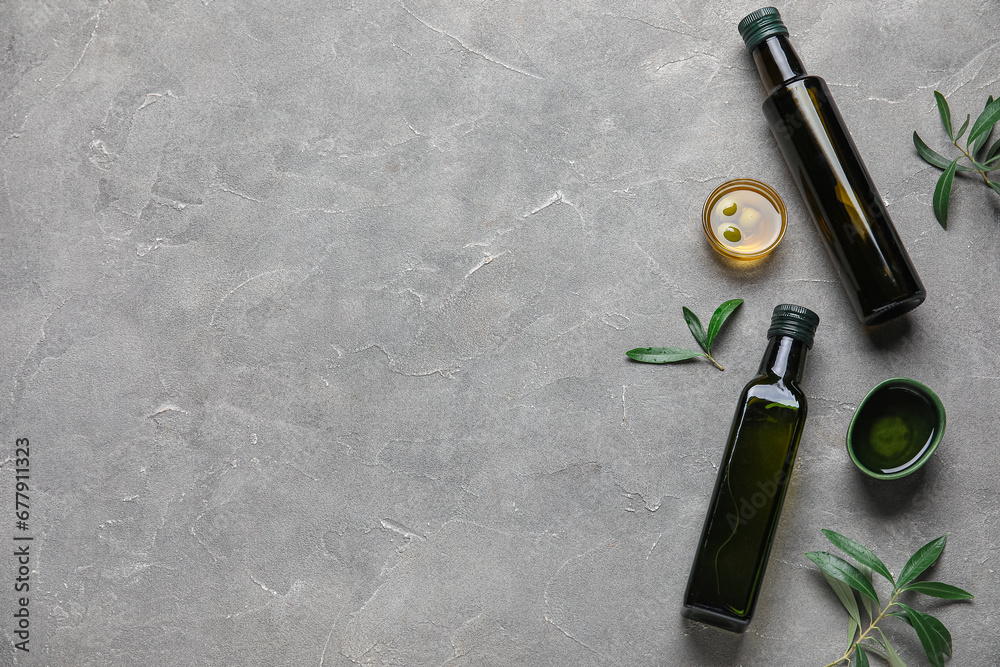 Bottles and bowls of fresh olive oil on grey background